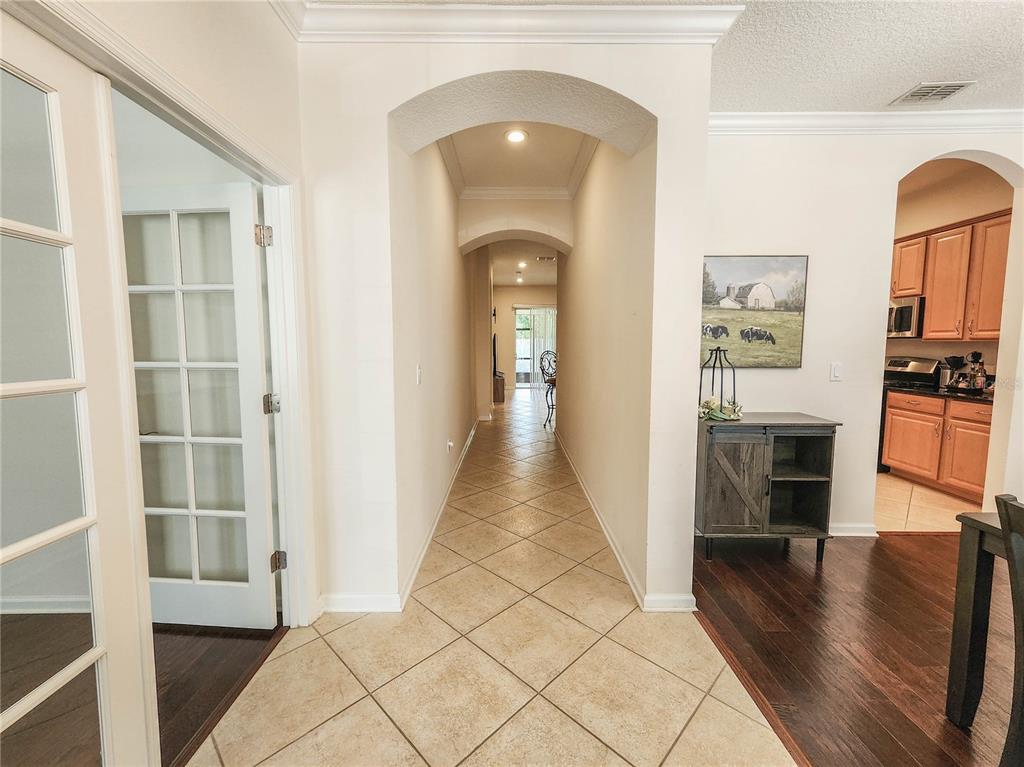 A tiled hallway with arched ceilings leads toward a distant doorway, flanked by a kitchen — 184 S ARABELLA WAY, ST JOHNS, FL