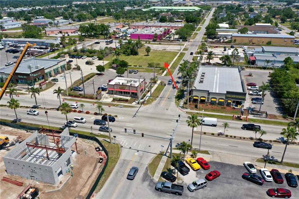 An aerial view shows a commercial intersection with a vacant lot, retail buildings, and parking — 122 E MCKENZIE STREET, PUNTA GORDA, FL