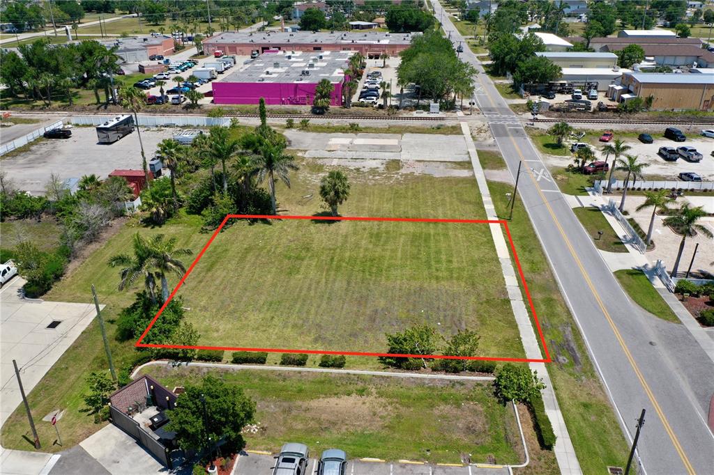 An aerial view shows a vacant, rectangular grass lot outlined in red next to a road — 122 E MCKENZIE STREET, PUNTA GORDA, FL