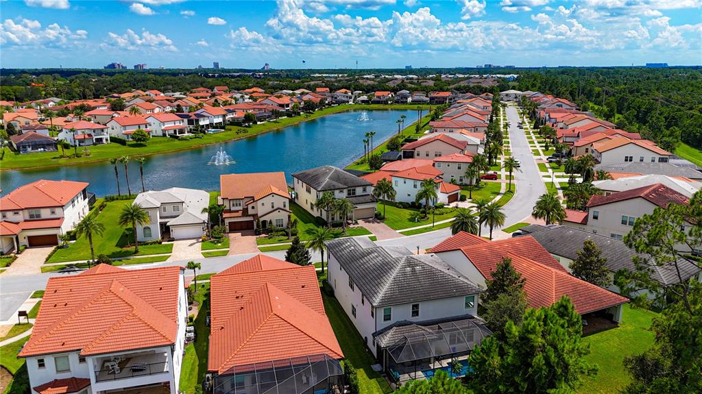An aerial view shows a suburban neighborhood with houses surrounding a central lake and fountain — 10427 ROYAL CYPRESS WAY, ORLANDO, FL