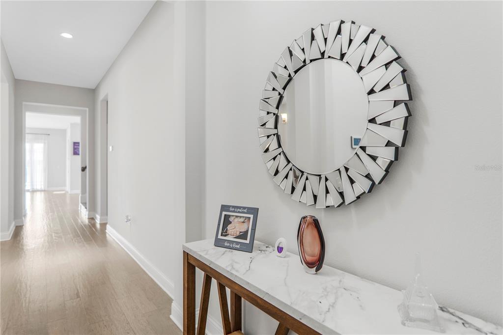 A hallway features a marble-topped console table with a decorative mirror on a white wall — 10427 ROYAL CYPRESS WAY, ORLANDO, FL