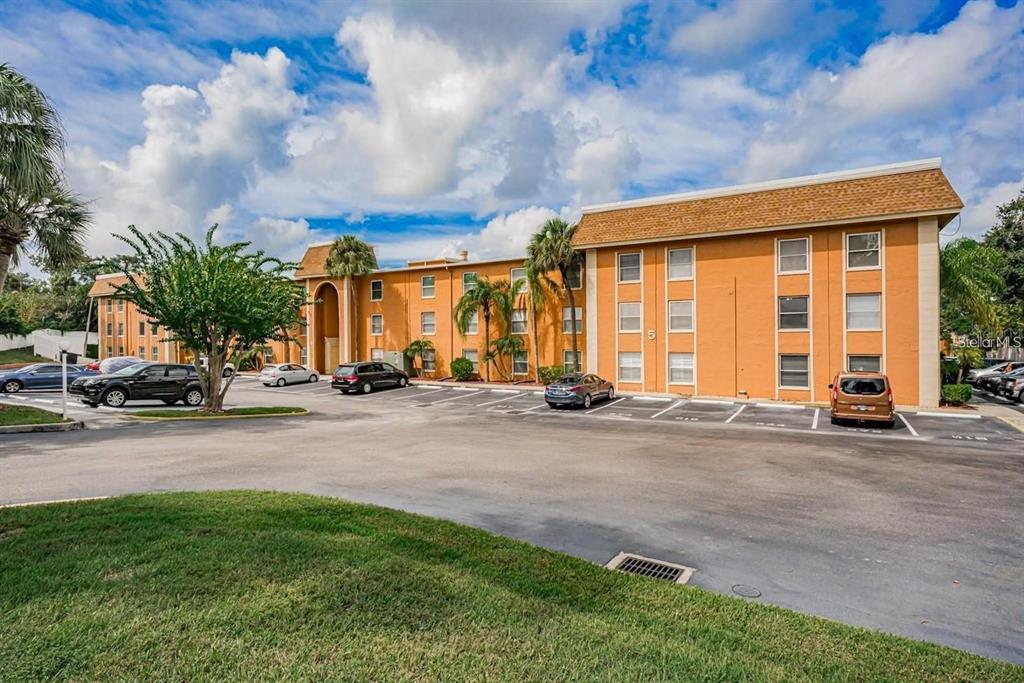 A three-story orange apartment building with a parking lot in front under a cloudy sky — 12760 INDIAN ROCKS ROAD UNIT 570, LARGO, FL