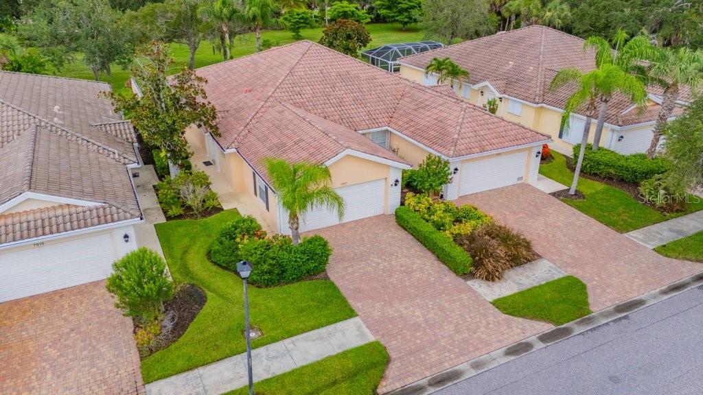 An aerial view of two adjacent single-story houses with tiled roofs and brick driveways — 7617 CAMMINARE DRIVE, SARASOTA, FL