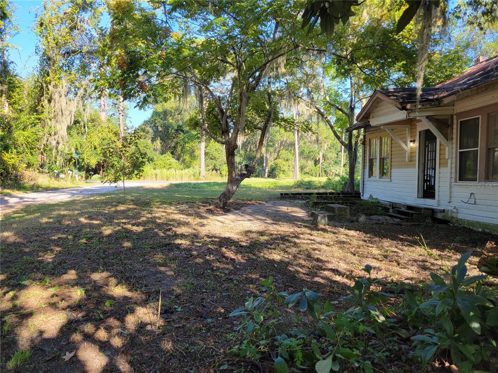 A side view of a house with a stone patio and surrounding trees — 15031 SE 189TH PLACE, HAWTHORNE, FL