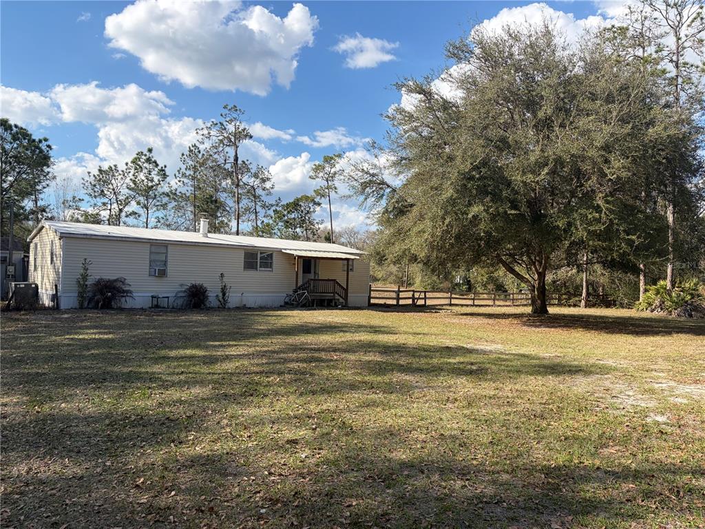 A single-story mobile home sits on a large grassy lot with a large oak tree — 6905 PEARSON LANE, WESLEY CHAPEL, FL