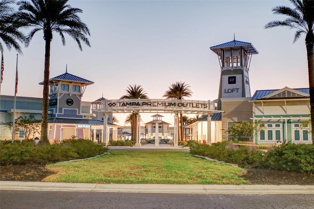 The exterior entrance of the Tampa Premium Outlets features palm trees and a central walkway — 6905 PEARSON LANE, WESLEY CHAPEL, FL