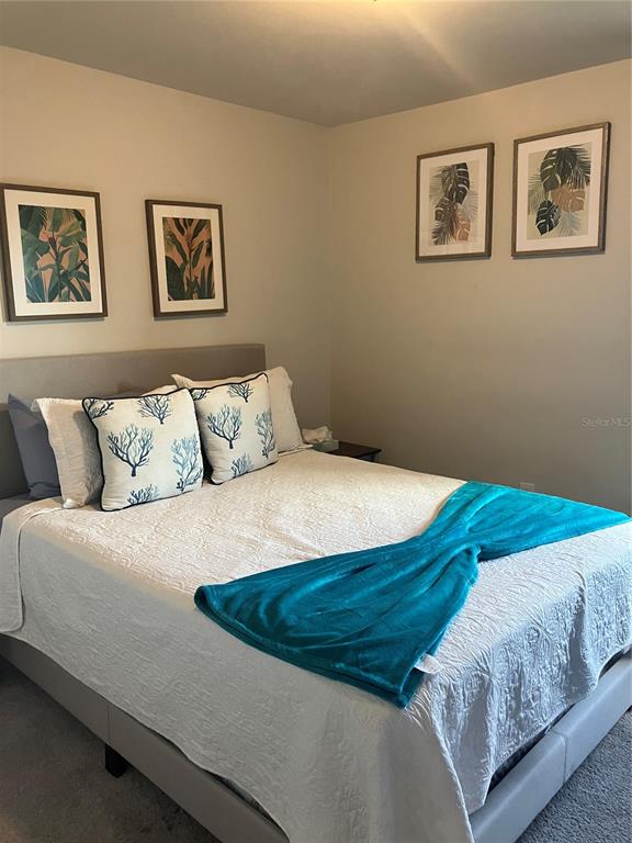 A bedroom features a bed with a white comforter, teal throw, and four framed botanical prints — 4109 NE 20TH PLACE, CAPE CORAL, FL