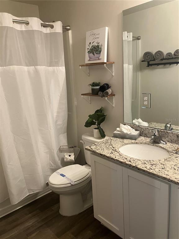 A bathroom features a white vanity with granite countertops, a toilet, and two wall-mounted shelves — 4109 NE 20TH PLACE, CAPE CORAL, FL