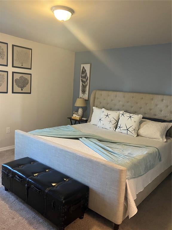 A bedroom features a tufted headboard, a black storage trunk, and blue accent wall paint — 4109 NE 20TH PLACE, CAPE CORAL, FL