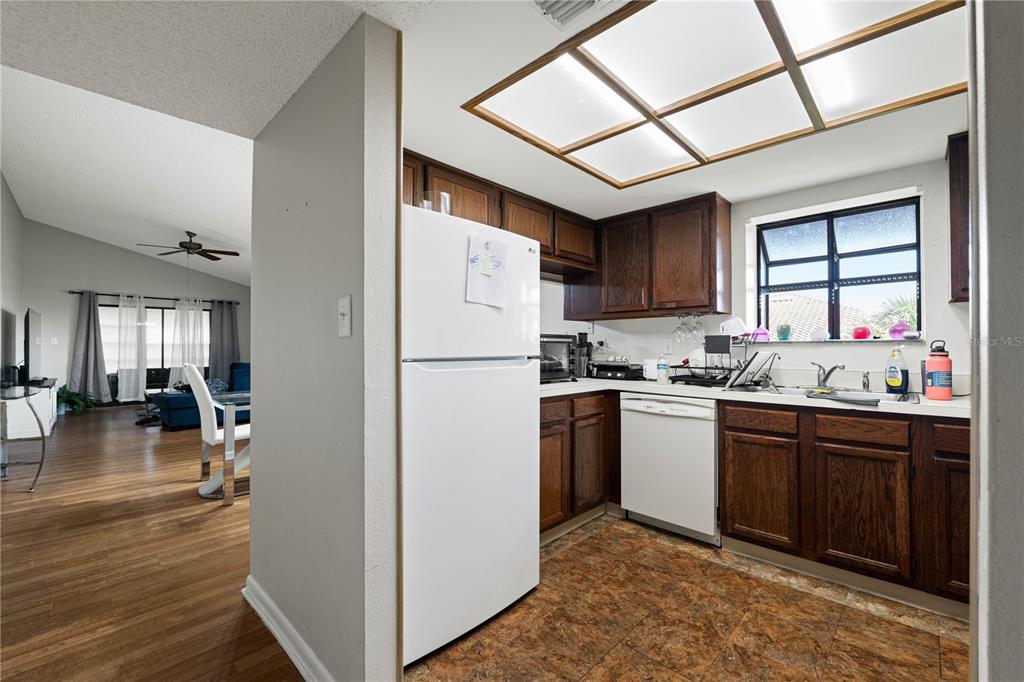 A kitchen with dark wood cabinets, white appliances, and a grid-style ceiling light fixture — 1109 HAMMOCK PINE BOULEVARD, CLEARWATER, FL