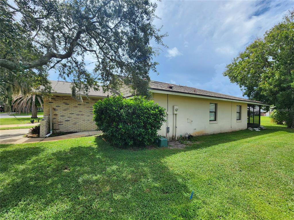 A side view of a single-story house with brick and stucco walls and a lawn — 322 PARADISE LANE, EDGEWATER, FL