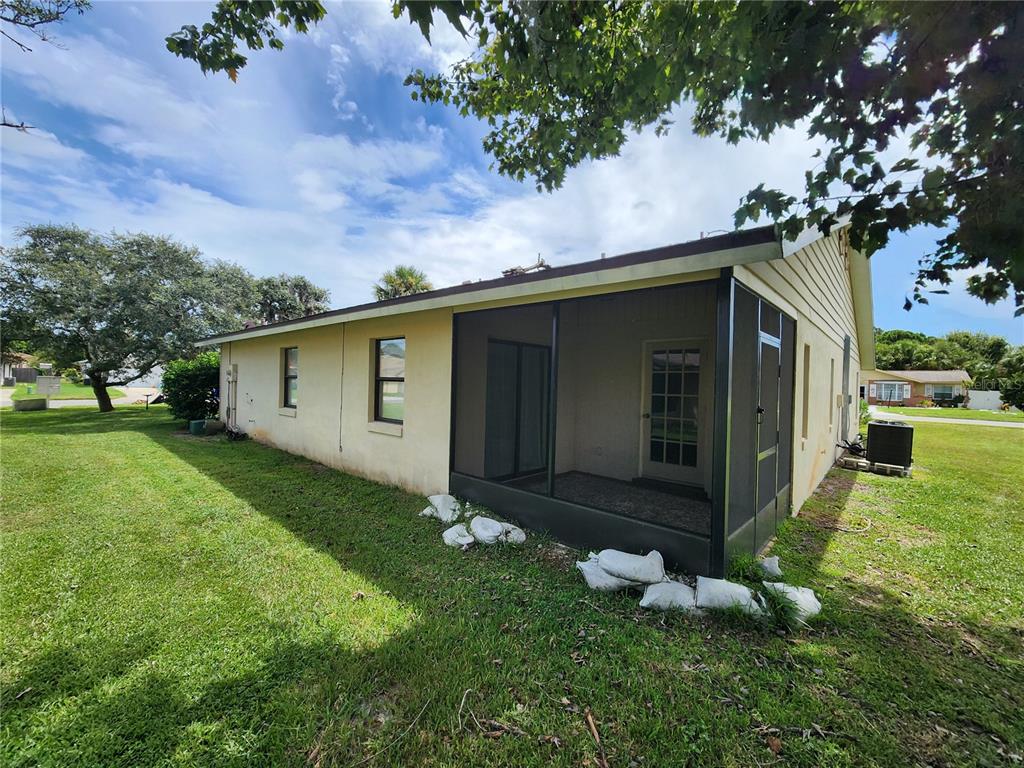 A side view of a house with a screened-in porch and sandbags along the base — 322 PARADISE LANE, EDGEWATER, FL