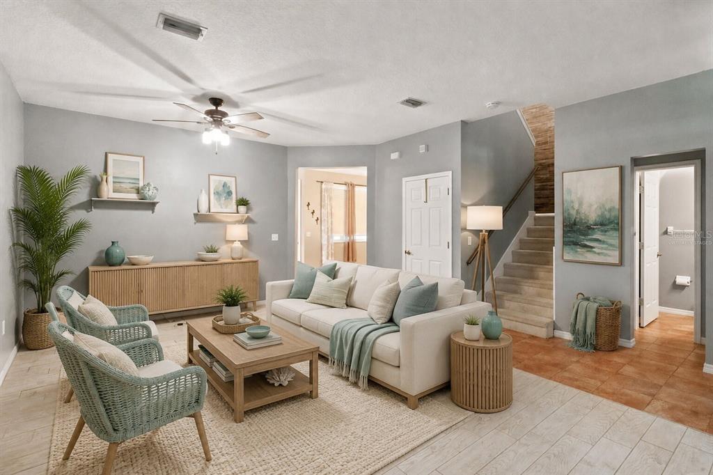 A living room features a sofa, two wicker chairs, a coffee table, and a staircase — 34928 TEEVIEW LANE, ZEPHYRHILLS, FL