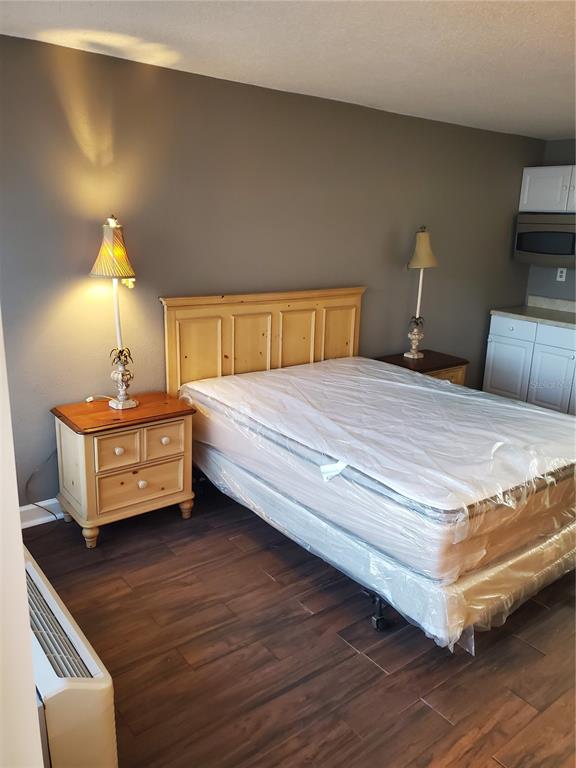 A bedroom features a bed with a plastic-covered mattress, two nightstands, and wood-look flooring — 7900 S ORANGE BLOSSOM TRAIL UNIT 2109, ORLANDO, FL