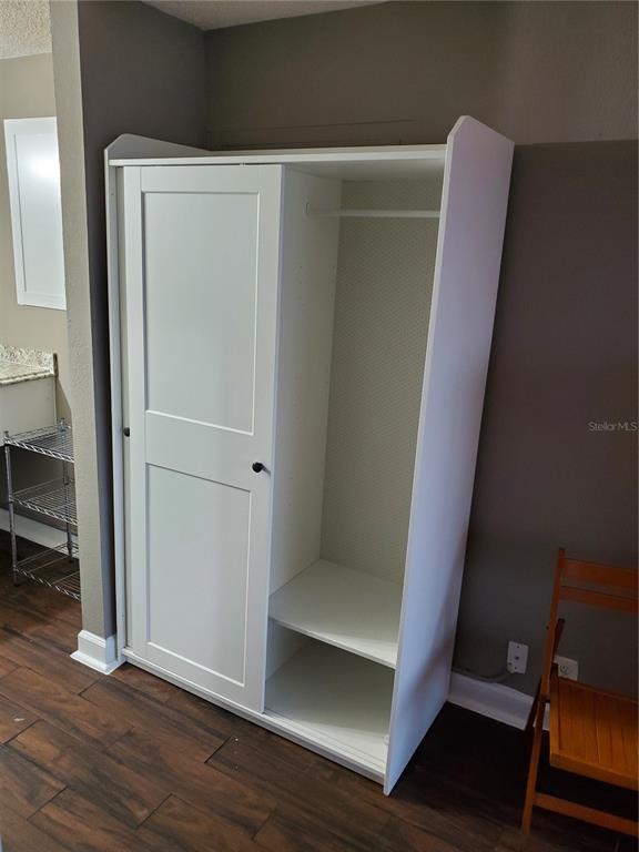 A white wardrobe with a sliding door stands in a room with dark wood flooring — 7900 S ORANGE BLOSSOM TRAIL UNIT 2109, ORLANDO, FL