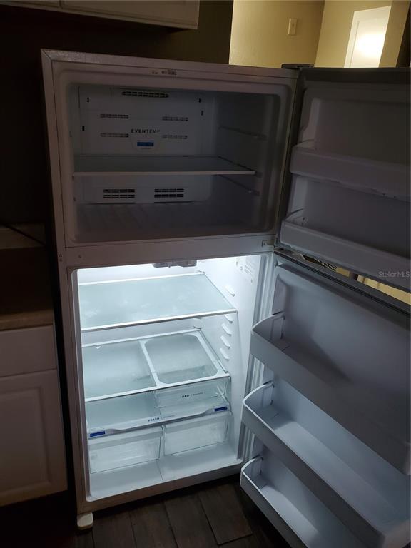 An open white refrigerator with multiple shelves and drawers stands in a kitchen — 7900 S ORANGE BLOSSOM TRAIL UNIT 2109, ORLANDO, FL