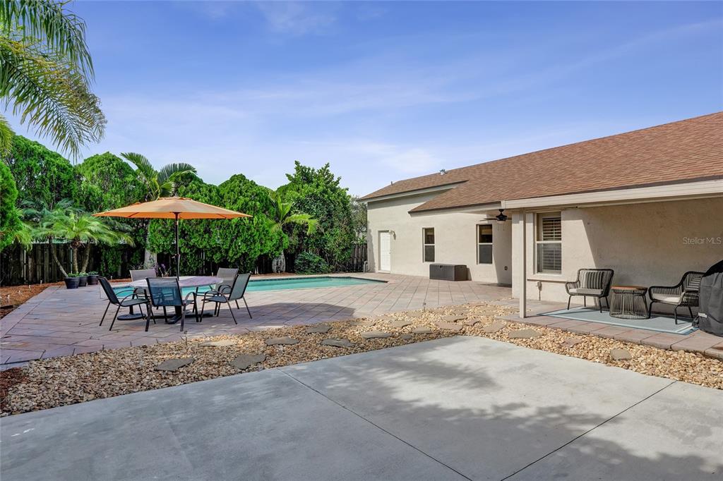 A backyard patio features a swimming pool, an orange umbrella, and outdoor seating — 1156 SW 149 LANE, SUNRISE, FL