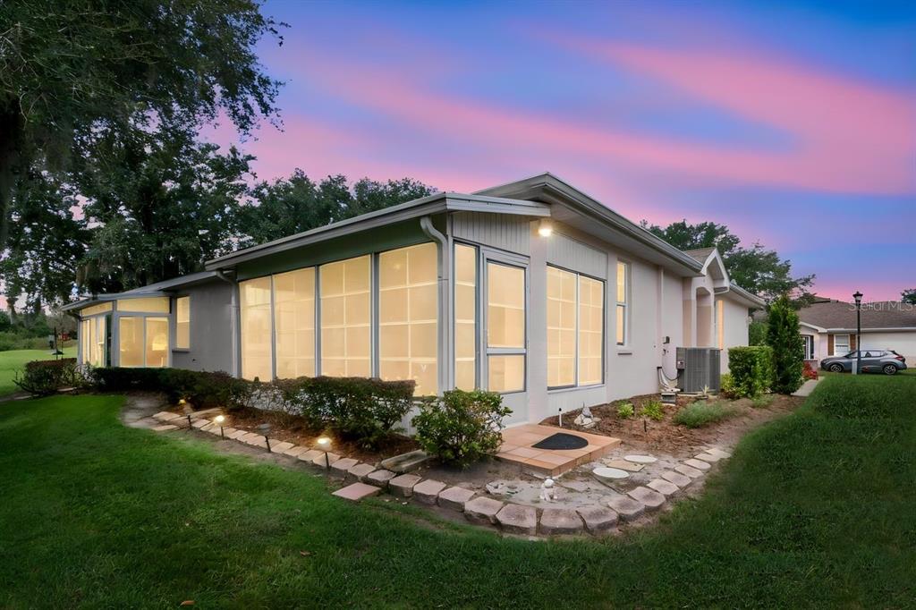 A single-story house exterior features a large glass-enclosed sunroom and a stone-bordered garden bed — 2635 EAGLE GREENS DRIVE, PLANT CITY, FL