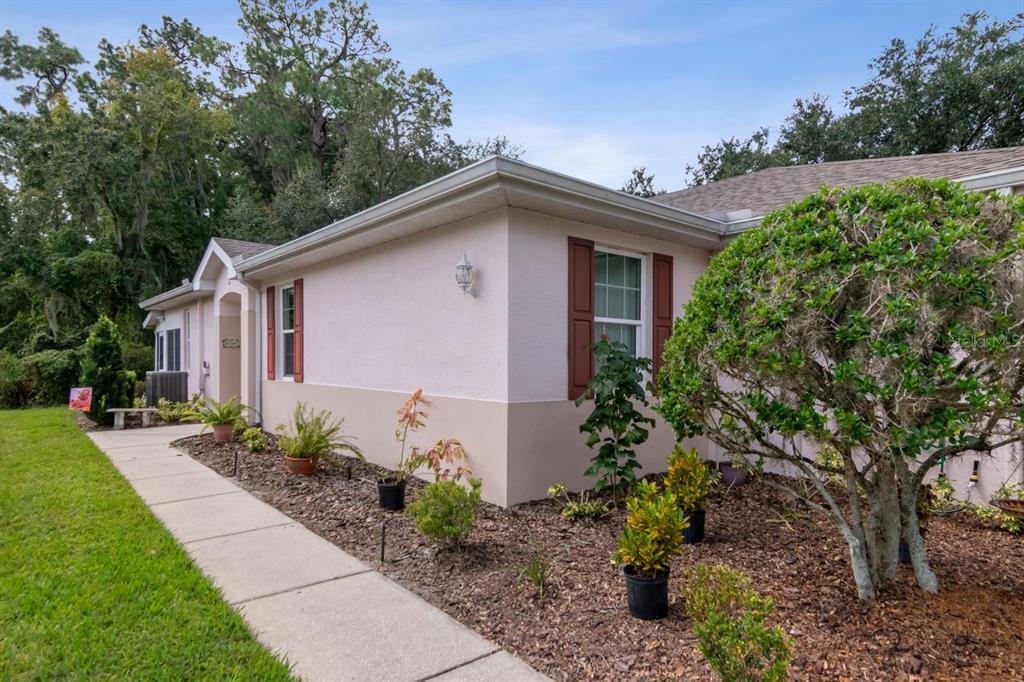 A light pink house exterior features a concrete walkway, brown shutters, and a landscaped yard — 2635 EAGLE GREENS DRIVE, PLANT CITY, FL