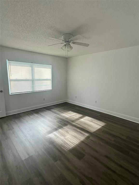 An empty living room features wood-look flooring, a ceiling fan, and sliding glass doors to a patio — 1060 DEES DRIVE, OVIEDO, FL