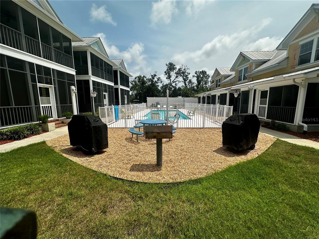 A swimming pool sits in front of a three-unit building with screened-in porches — 206 SE TENTH STREET UNIT 9, STEINHATCHEE, FL