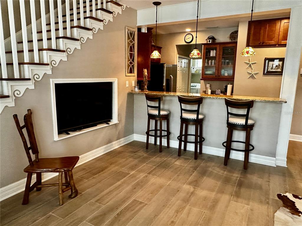 A kitchen with a breakfast bar, three stools, and a dining area with wood flooring — 206 SE TENTH STREET UNIT 9, STEINHATCHEE, FL