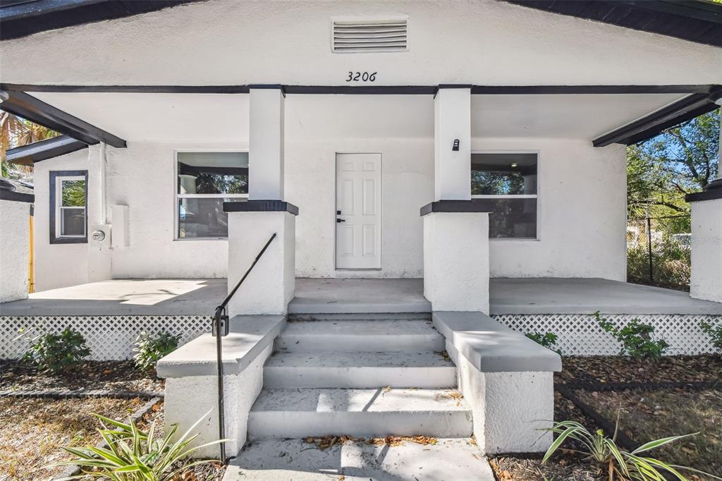 The exterior of a white house features a covered front porch with concrete steps — 3206 N 29TH STREET, TAMPA, FL