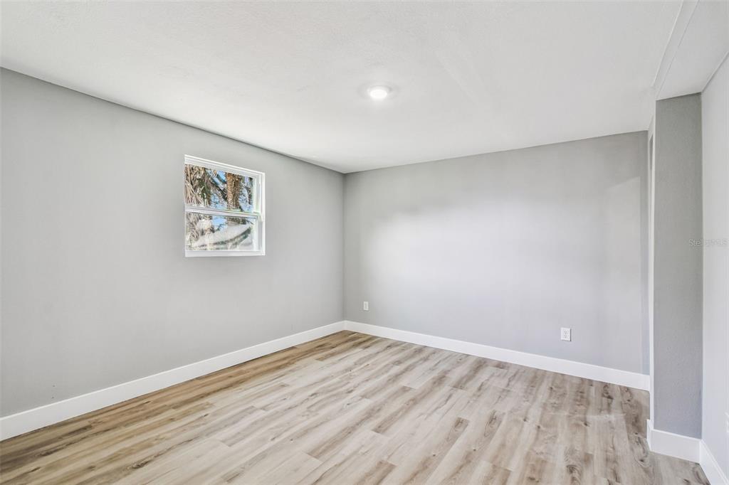 An empty bedroom features light gray walls, wood-look flooring, and a single window — 3206 N 29TH STREET, TAMPA, FL