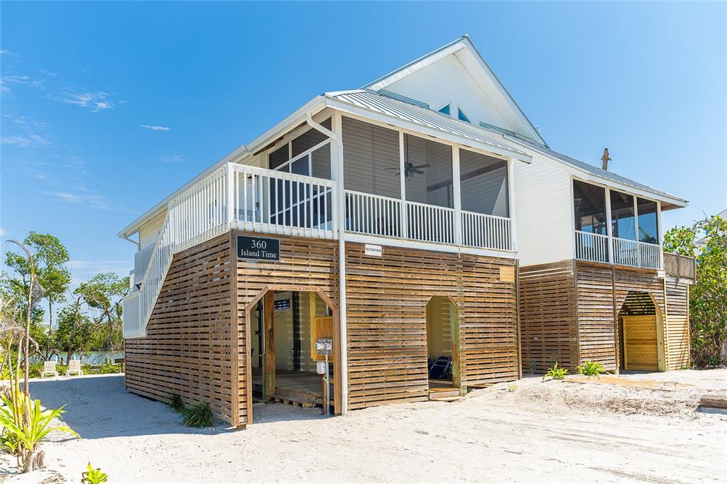 A stilt house with horizontal wood siding, a screened porch, and an outdoor staircase — 360 S GULF BOULEVARD, PLACIDA, FL