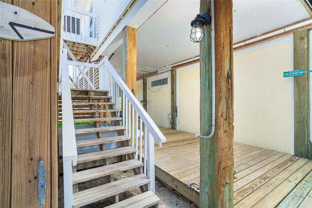 A wooden staircase leads to an elevated deck beneath a stilt house with yellow siding — 360 S GULF BOULEVARD, PLACIDA, FL