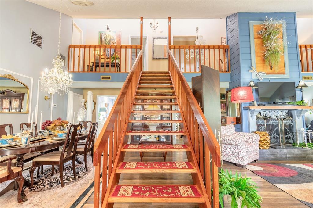 A wooden staircase leads to a loft overlooking a dining room and living area — 3130 ROYAL PALM DRIVE, EDGEWATER, FL