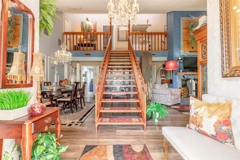 A grand foyer features a central wooden staircase, a crystal chandelier, and an open loft — 3130 ROYAL PALM DRIVE, EDGEWATER, FL
