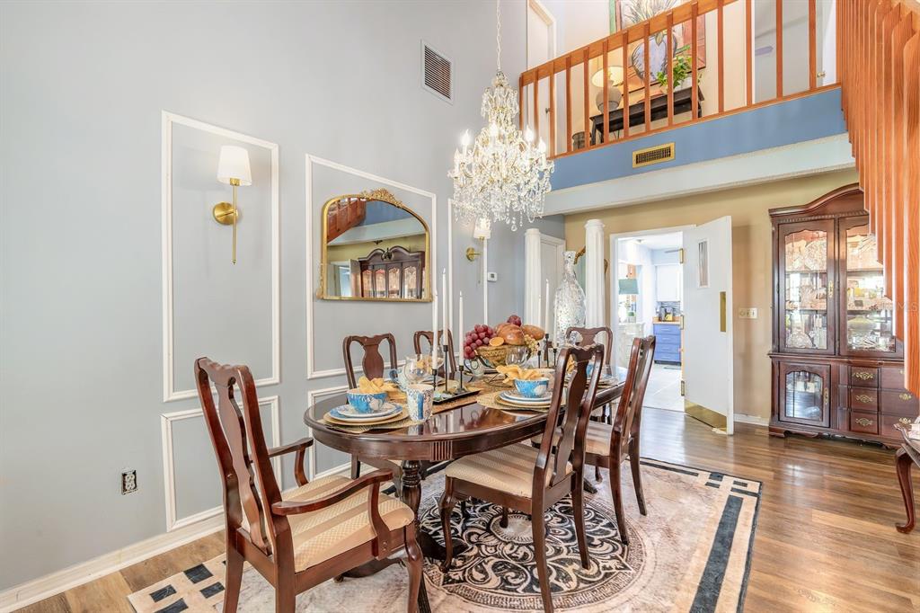 A formal dining room features a crystal chandelier, wood furniture, and a two-story ceiling — 3130 ROYAL PALM DRIVE, EDGEWATER, FL