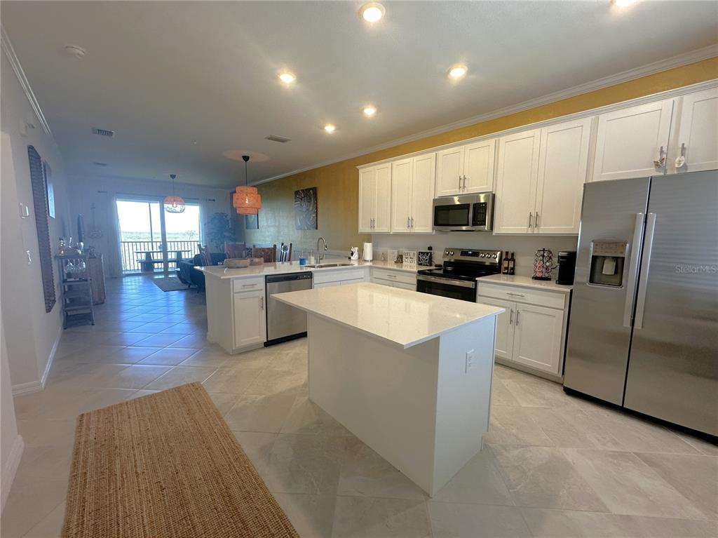 A kitchen with white cabinets, stainless steel appliances, and a central island with quartz countertops — 14211 HERITAGE LANDING BOULEVARD UNIT 1444, PUNTA GORDA, FL
