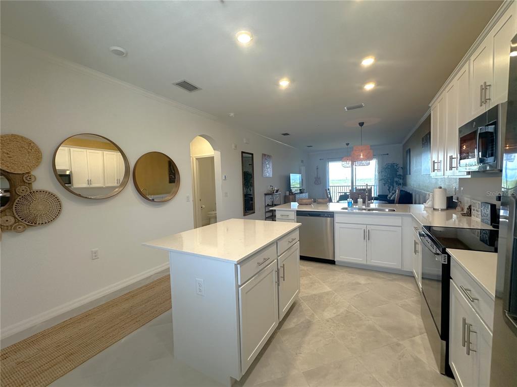 A modern kitchen features white cabinetry, a central island, and light-colored tile flooring — 14211 HERITAGE LANDING BOULEVARD UNIT 1444, PUNTA GORDA, FL