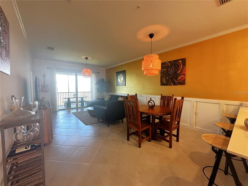 A dining area with a wooden table and chairs sits adjacent to a living room — 14211 HERITAGE LANDING BOULEVARD UNIT 1444, PUNTA GORDA, FL