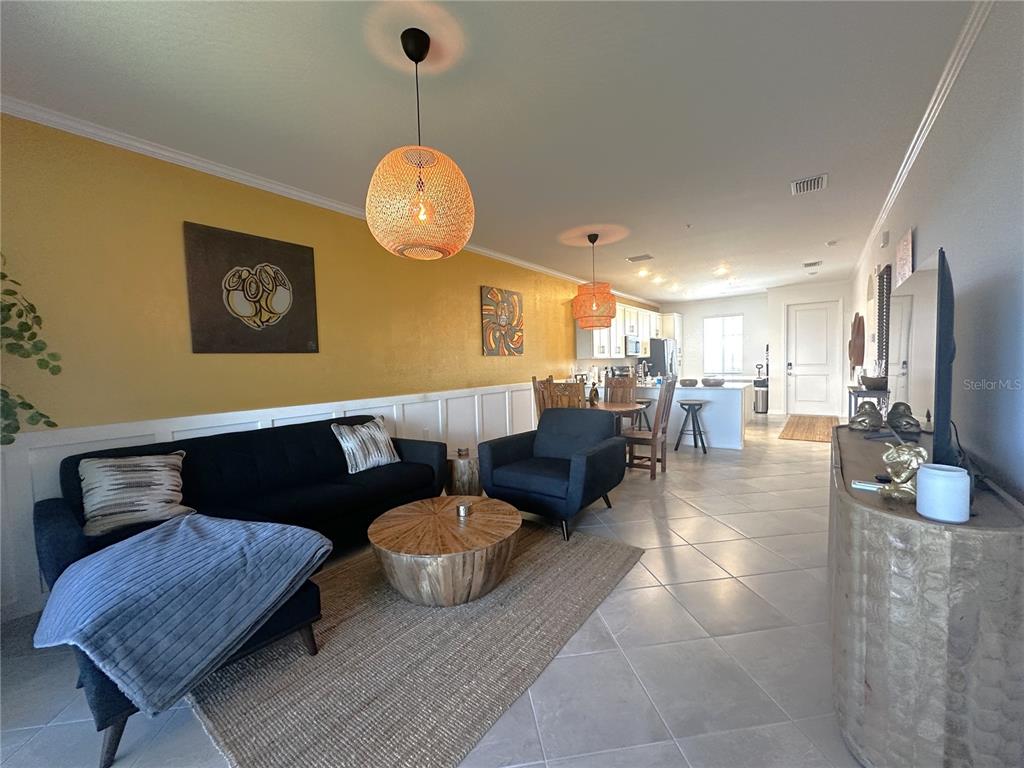 An open-concept living room features a yellow accent wall, dark furniture, and tile flooring — 14211 HERITAGE LANDING BOULEVARD UNIT 1444, PUNTA GORDA, FL