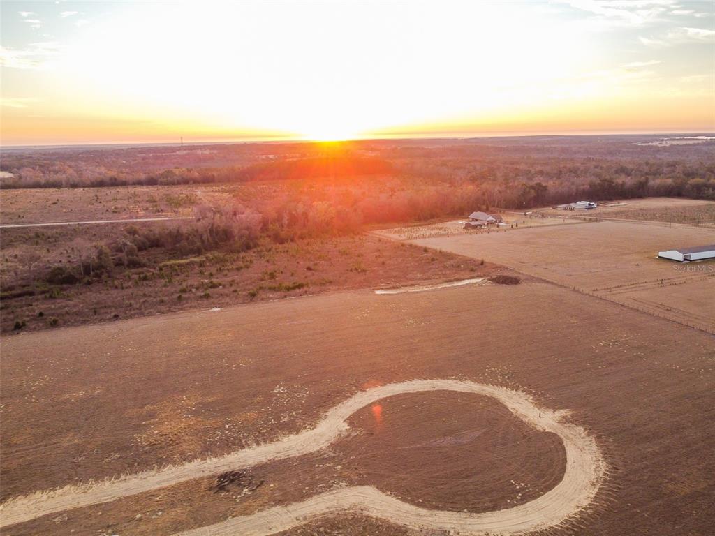 An aerial view shows a dirt cul-de-sac in a large, open field at sunset — 4138 ROYAL SKY (LOT 10) COURT, BROOKSVILLE, FL