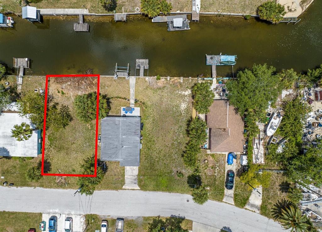 An aerial view shows a vacant waterfront lot outlined in red next to a house — 6837 SANDERLING LANE, HUDSON, FL