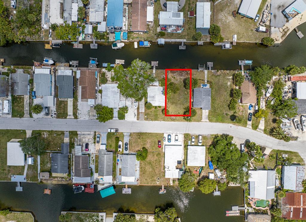 This aerial view shows a vacant waterfront lot outlined in red within a residential neighborhood — 6837 SANDERLING LANE, HUDSON, FL