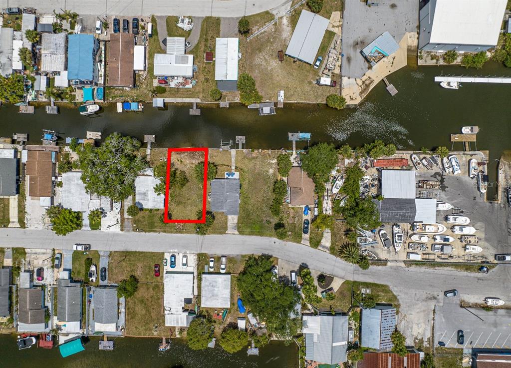 An aerial view shows a vacant waterfront lot outlined in red between two houses — 6837 SANDERLING LANE, HUDSON, FL