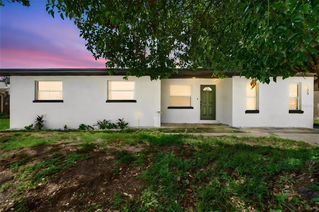 A single-story white house with a green front door and a large tree in front — 655 TRAVIS COURT, BARTOW, FL