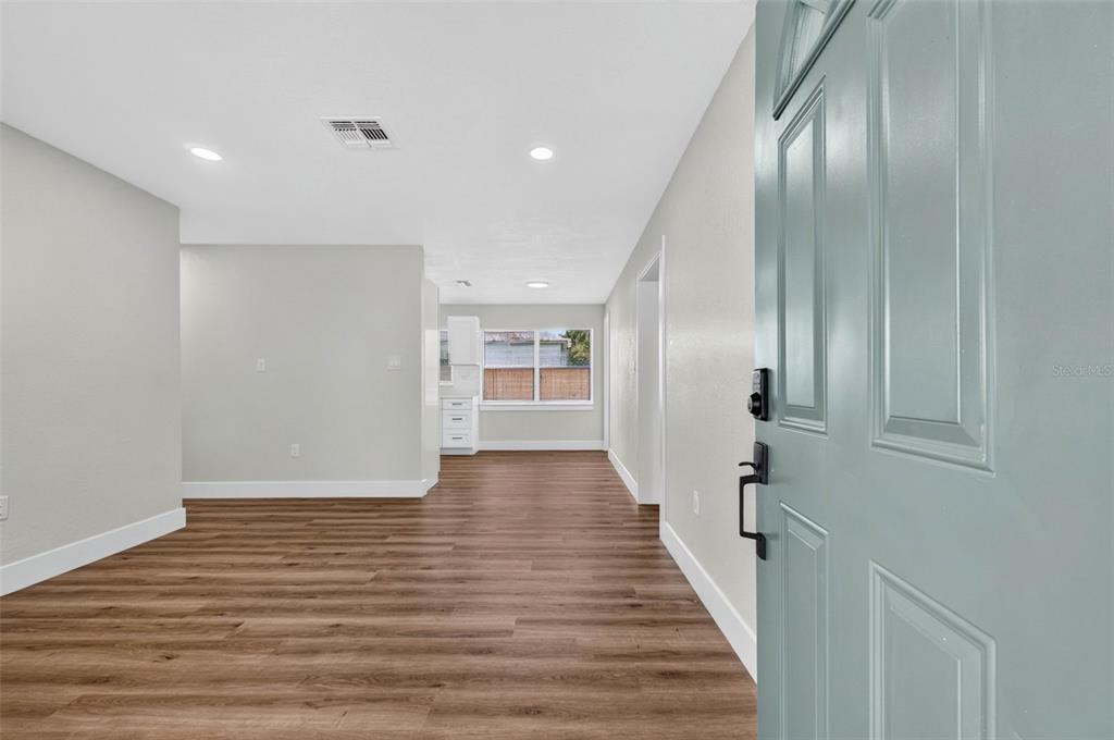 An open-concept living area features light gray walls, wood-look flooring, and a blue front door — 655 TRAVIS COURT, BARTOW, FL