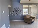 A living room features gray walls, a decorative wall decal, tile flooring, and an armchair — 1403 KISSIMMEE COURT, POINCIANA, FL