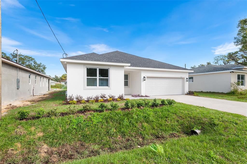A single-story white house with a two-car garage and a landscaped front lawn — 2519 AVENUE E SW, WINTER HAVEN, FL