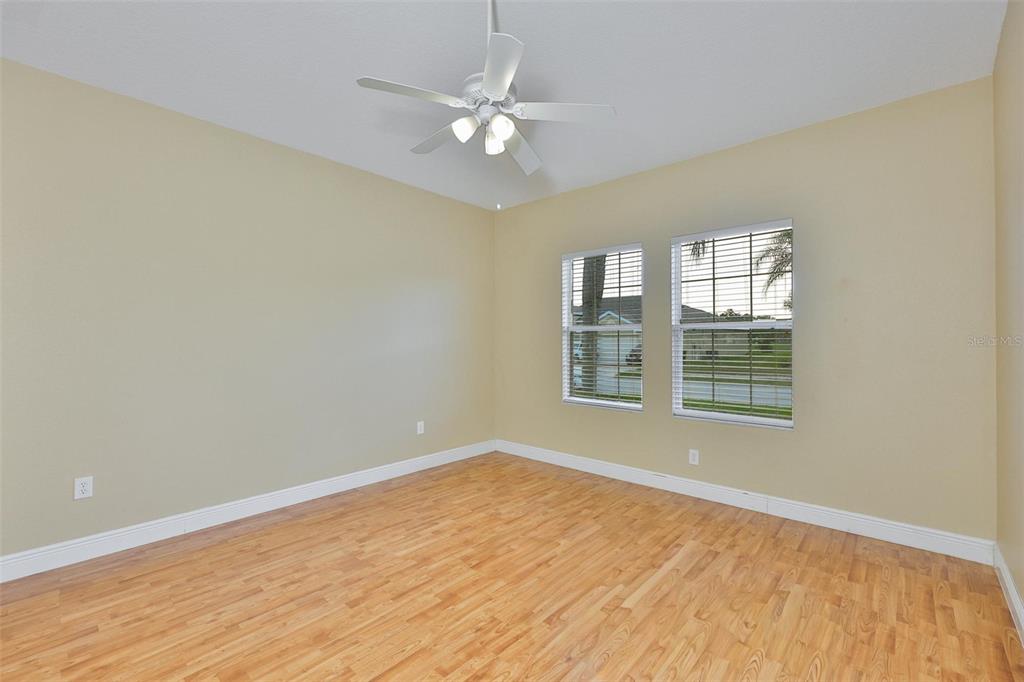 An empty bedroom features light-colored walls, wood-look flooring, a ceiling fan, and two windows — 11813 STONEWOOD GATE DRIVE, RIVERVIEW, FL