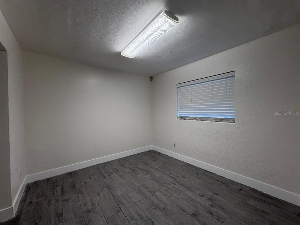 An empty room with gray wood-look tile flooring, white walls, and a rectangular ceiling light — 498 ESTHER LANE, ALTAMONTE SPRINGS, FL