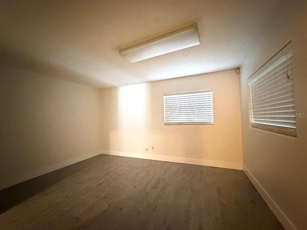 An empty room features light-colored walls, gray wood-look flooring, two windows with blinds, and lighting — 498 ESTHER LANE, ALTAMONTE SPRINGS, FL