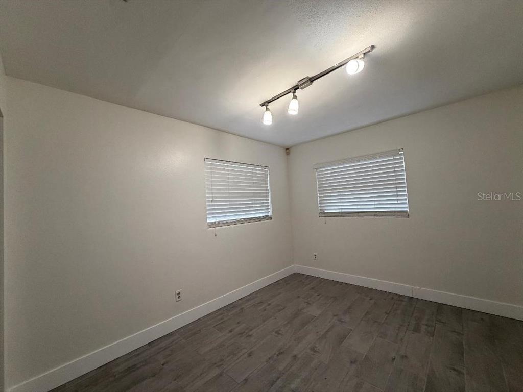 An empty bedroom features white walls, gray wood-look flooring, two windows with blinds, and track lighting — 498 ESTHER LANE, ALTAMONTE SPRINGS, FL
