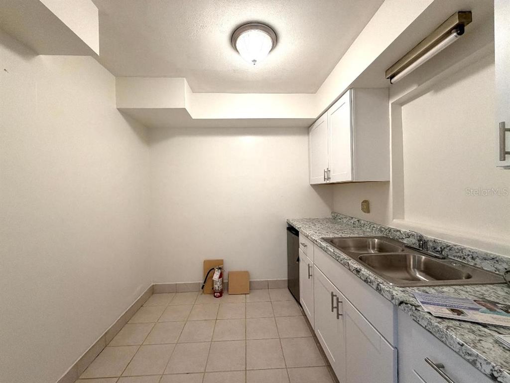 A kitchen features white cabinets, granite-look countertops, a double-basin sink, and tiled flooring — 498 ESTHER LANE, ALTAMONTE SPRINGS, FL